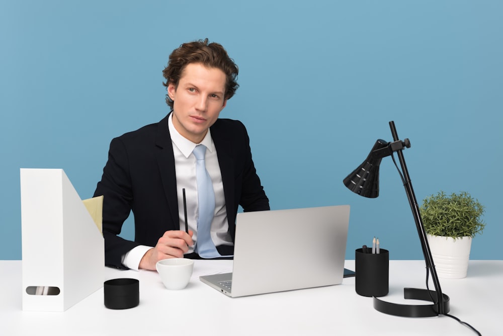 Homme assis sur une chaise à côté d’un ordinateur portable et d’une tasse de thé