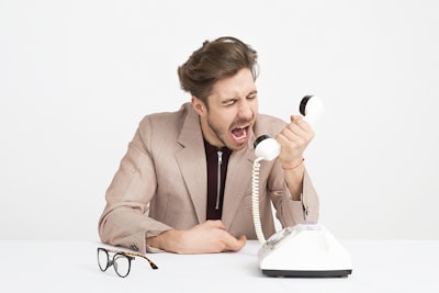 man holding telephone screaming annoyed teams background