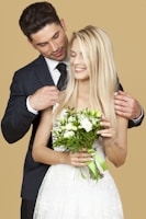 married couple standing beside beige wall
