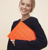 smiling woman standing while holding orange folder