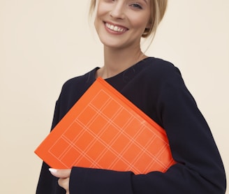 smiling woman standing while holding orange folder