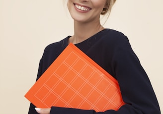 smiling woman standing while holding orange folder