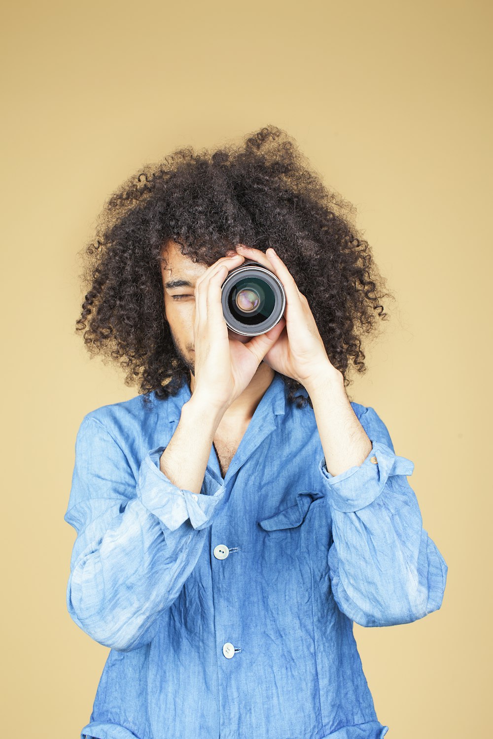 man wearing blue dress shirt using zoom lens