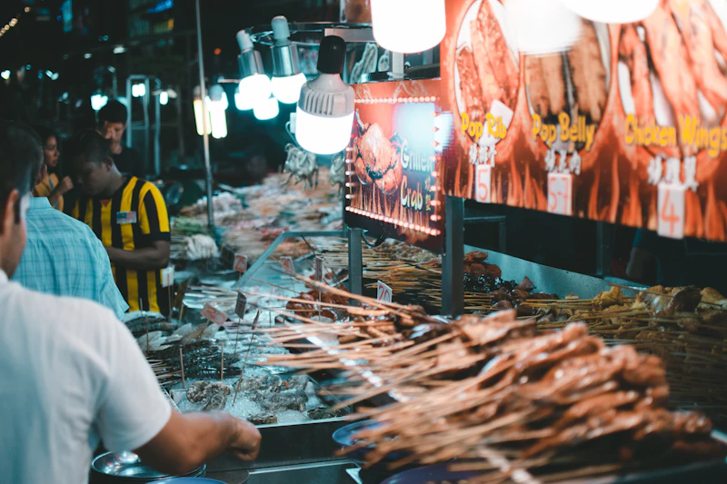 Guests gathered at a grilled-skewer stall at an evening food market