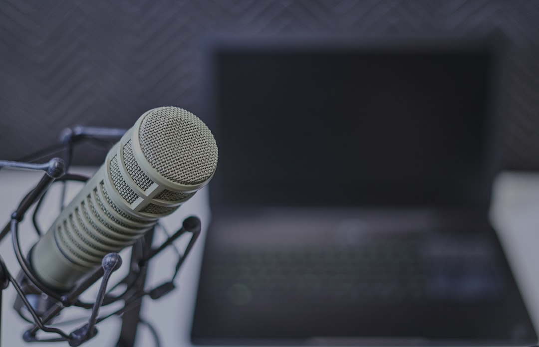 Image of a professional microphone in front of a laptop with a blurry background