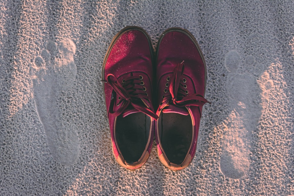 pair of red sneakers on sand