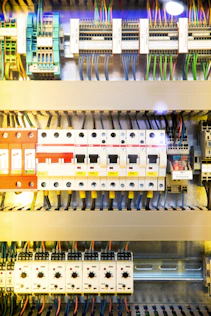 Electricians wiring a complex switchgear panel with precision and care.