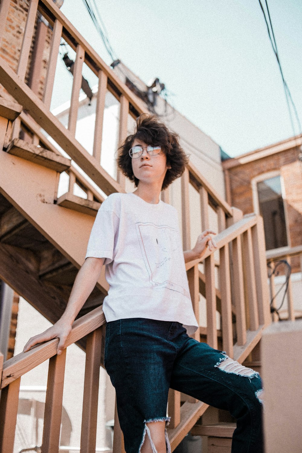 woman wearing white crew-neck t-shirt and distressed blue denim jeans standing on stairs during daytime