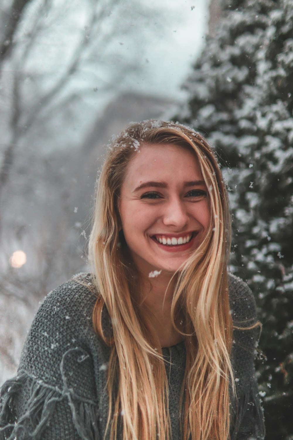 smiling woman standing wearing gray sweater