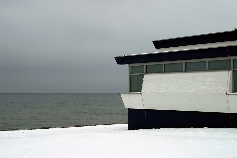수역 근처의 눈 덮인 해변에 있는 흰색과 검은색 집
