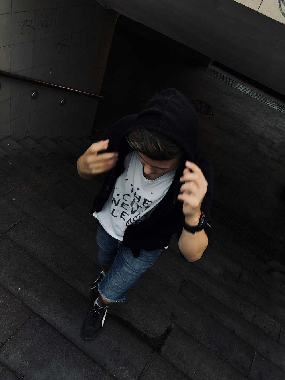 man wearing black zip-up hoodie walking in stair tunnel