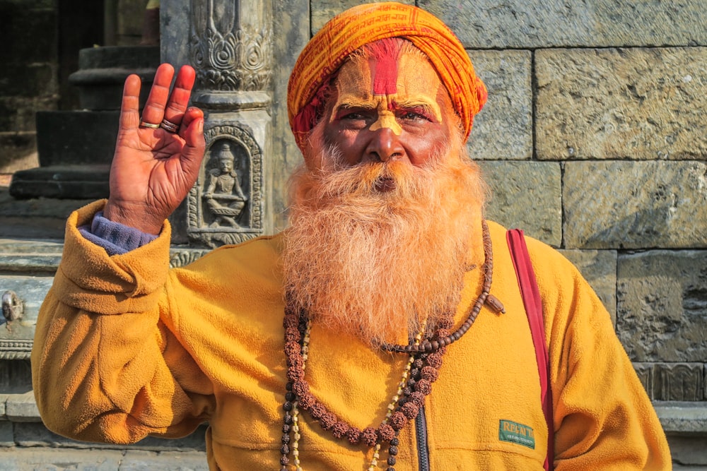 man wearing yellow zip-up jacket doing ok hand sign during daytime