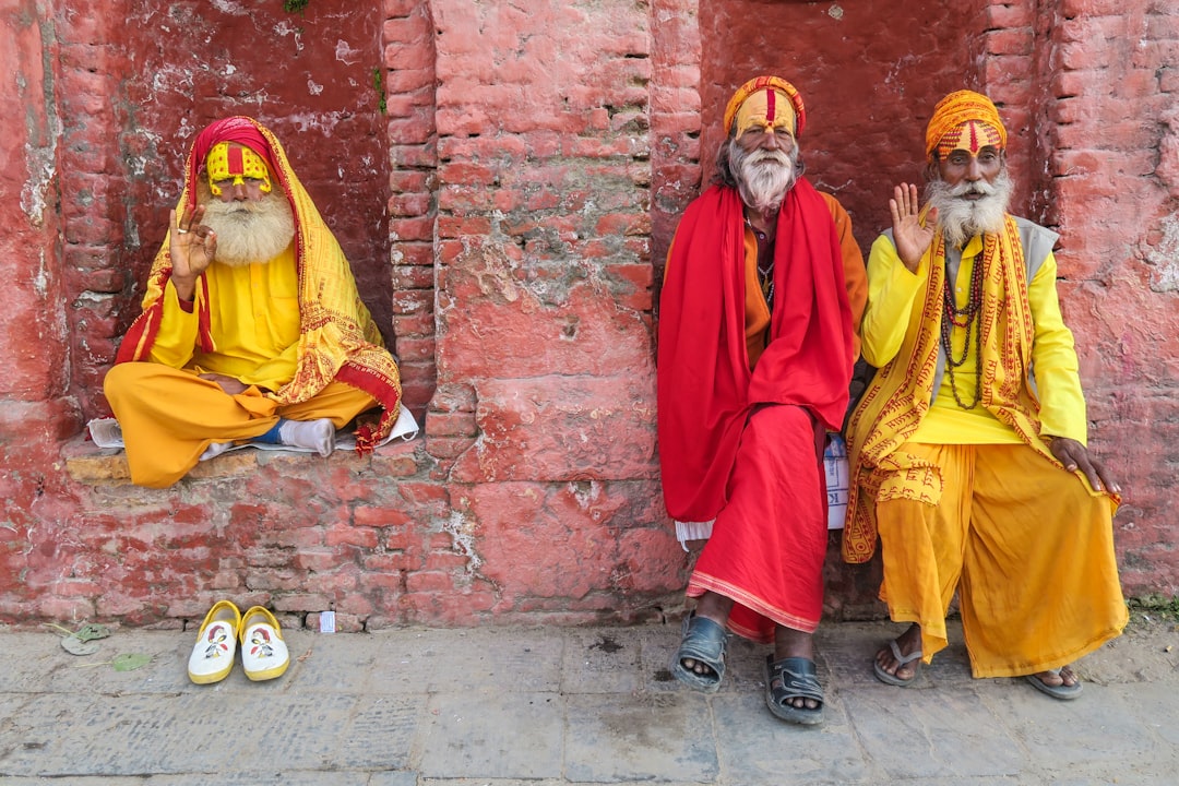 three religious men in yellow and red robes sitting by the red brink building