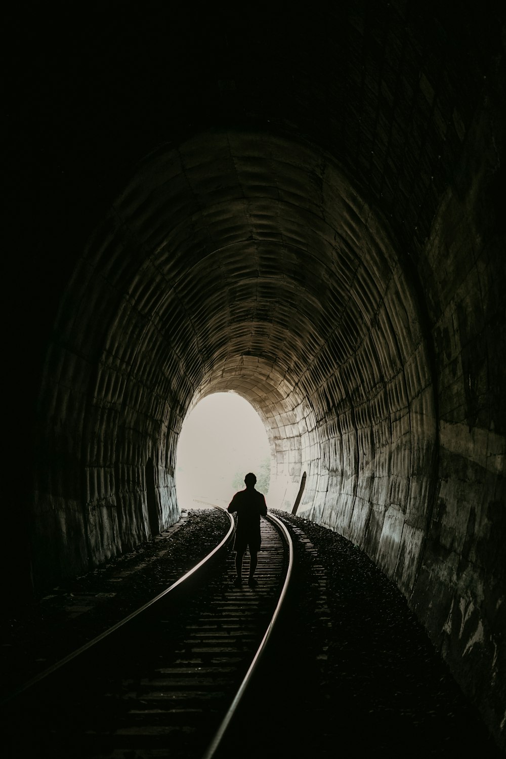silhouette photography of person walking at tunnel