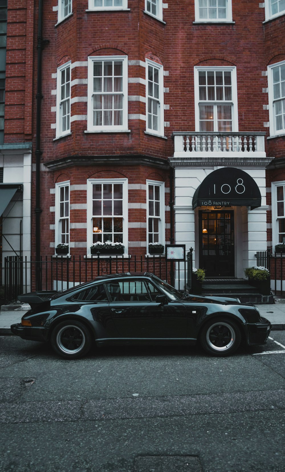 green coupe parked near the red and white building during daytime