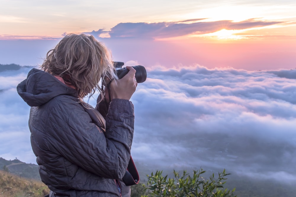 woman taking photo of clouds