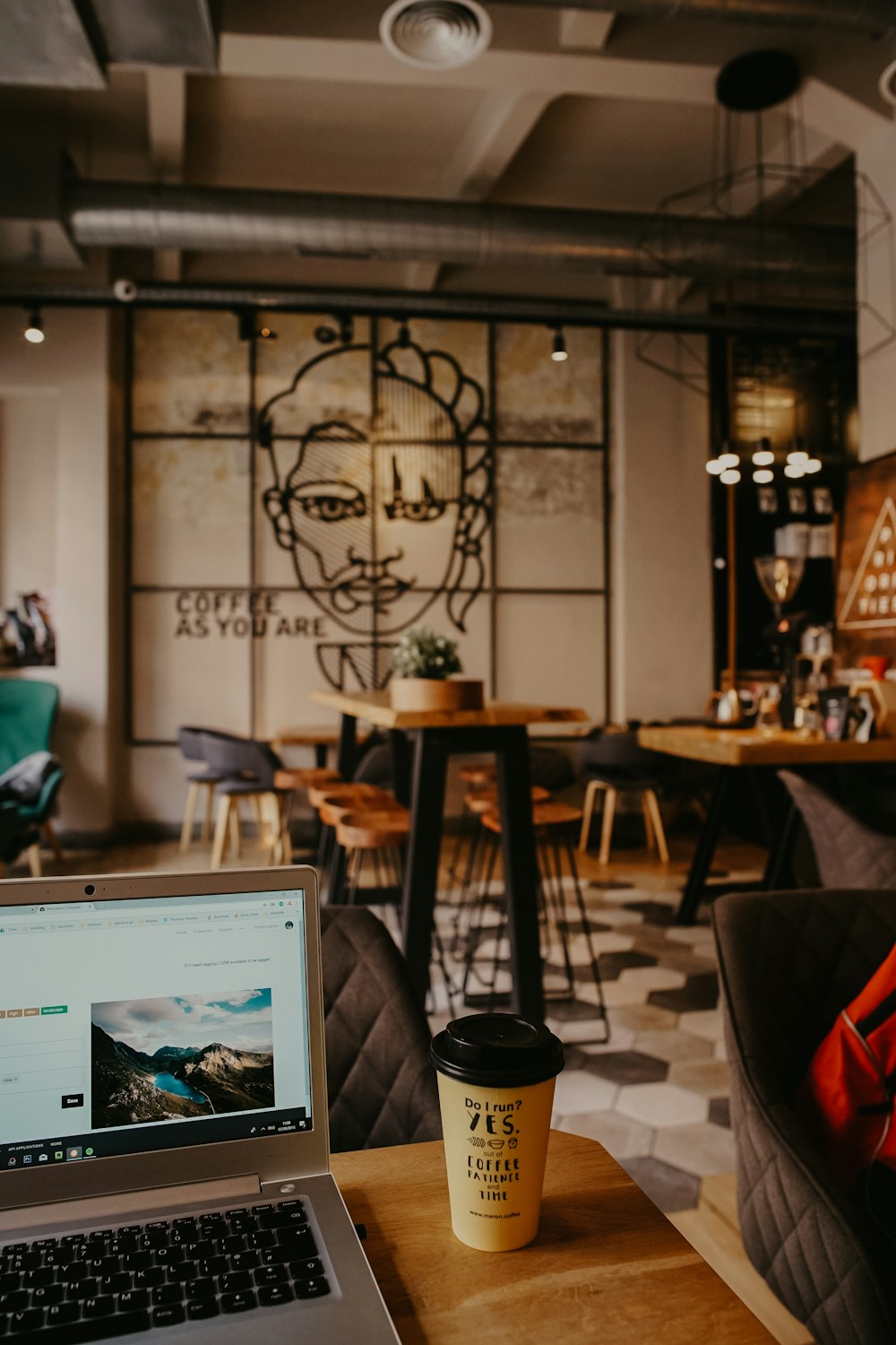 brown coffee cup beside laptop