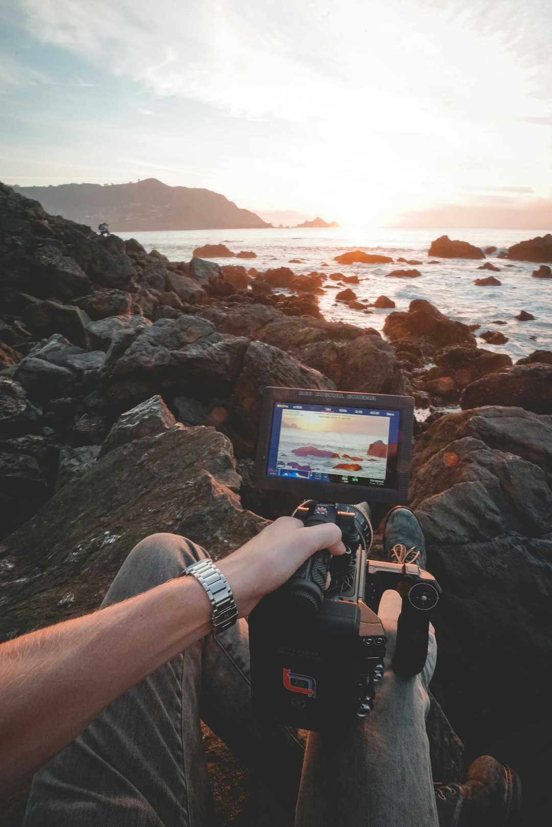 person taking photo of seashore using professional camera