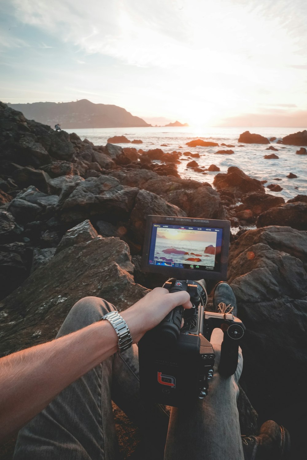 person taking photo of seashore using professional camera