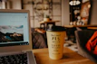 Casual lifestyle shot of a person using a laptop and sipping coffee in a cozy nook.