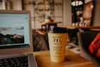 Casual lifestyle shot of a person using a laptop and sipping coffee in a cozy nook.