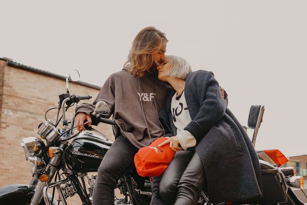 man kissing woman's forehead while sitting on motorcycle