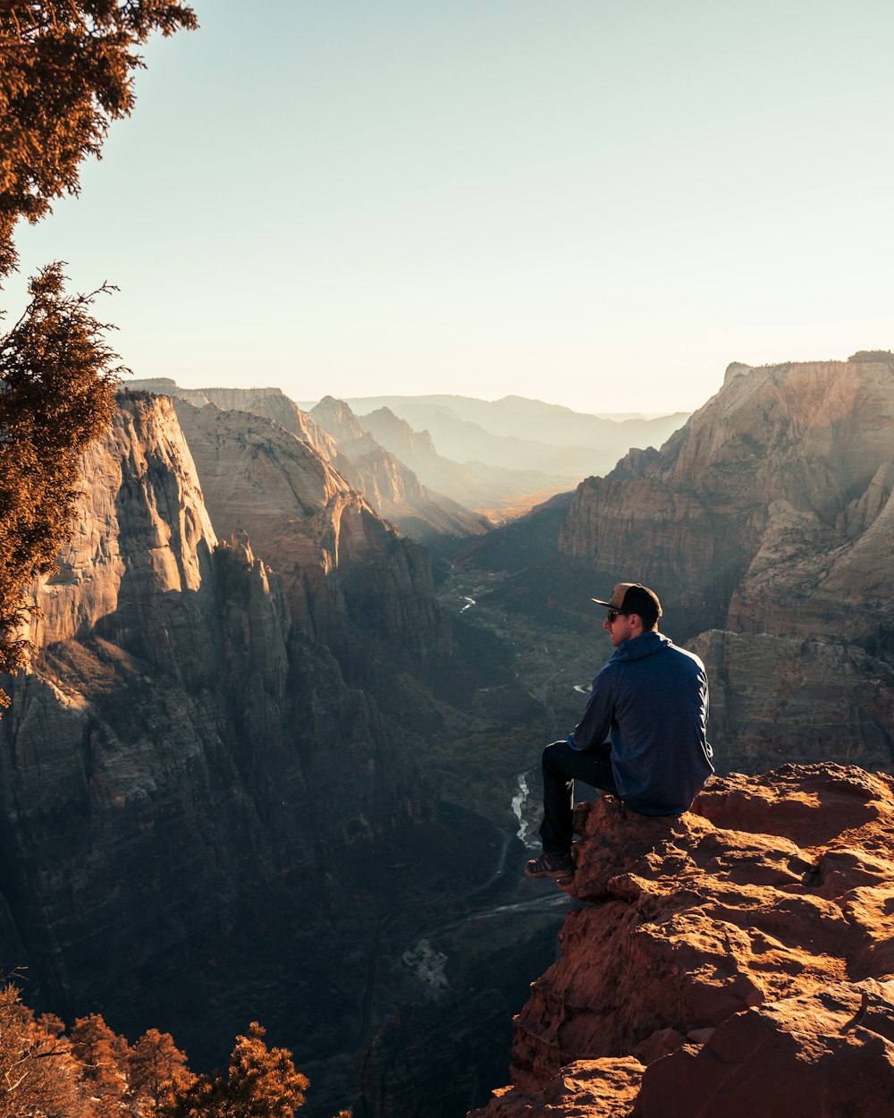 man sitting on cliff of canyon during daytime