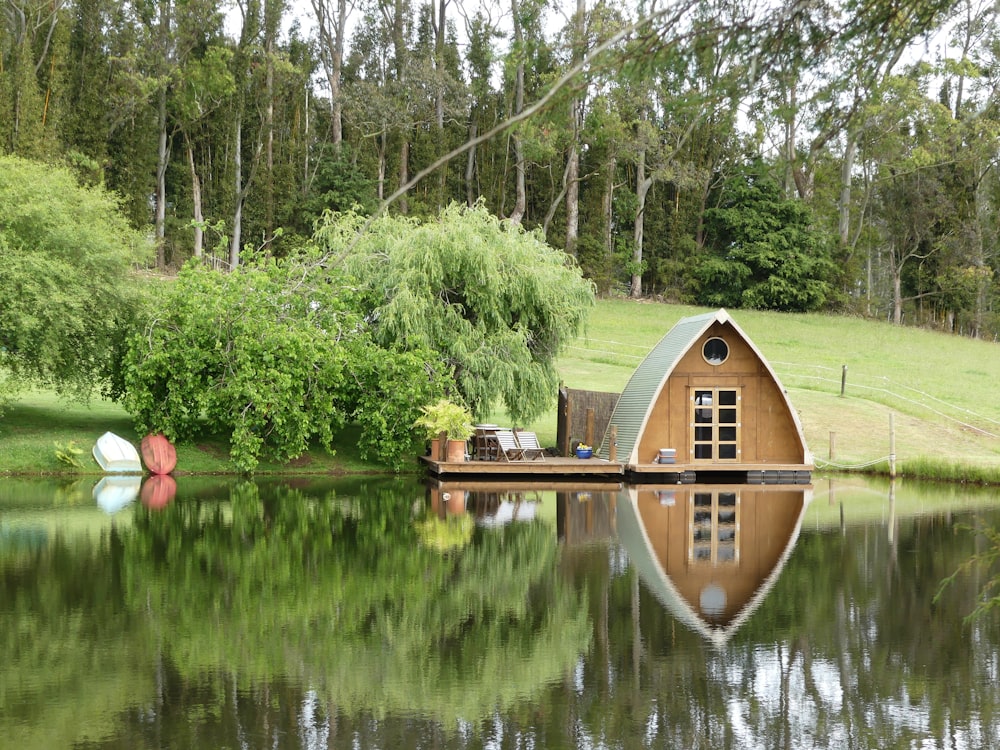 brown wooden cabin near calm water and green trees