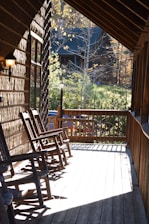 Chalet porch with rocking chairs overlooking a peaceful forest landscape.