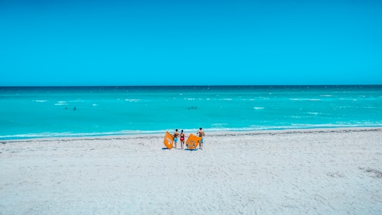 A happy family enjoying a sunny beach with turquoise waters and bright orange beach towels.