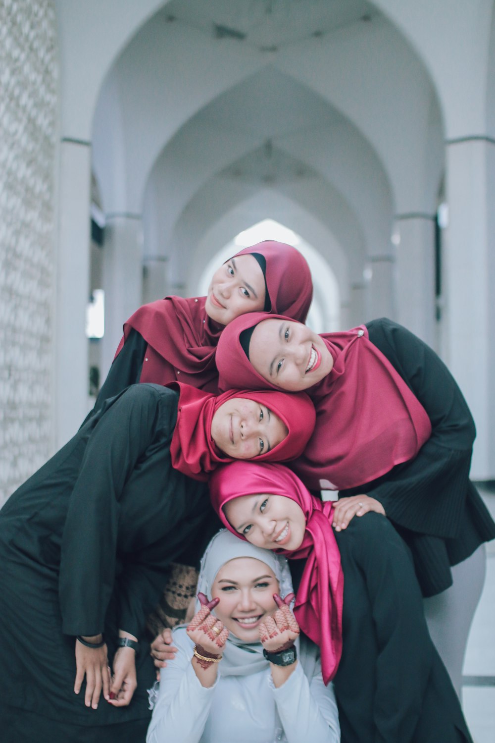 five women wearing hijab leaning each other