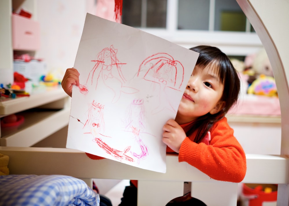 muchacha sosteniendo papel con dibujo