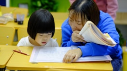 A visually impaired child learning with the help of a volunteer.