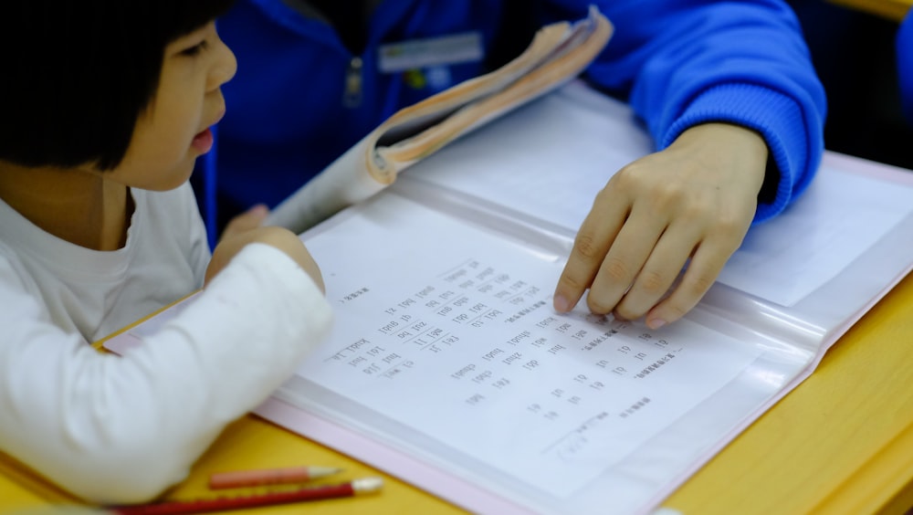 person teaching girl using book