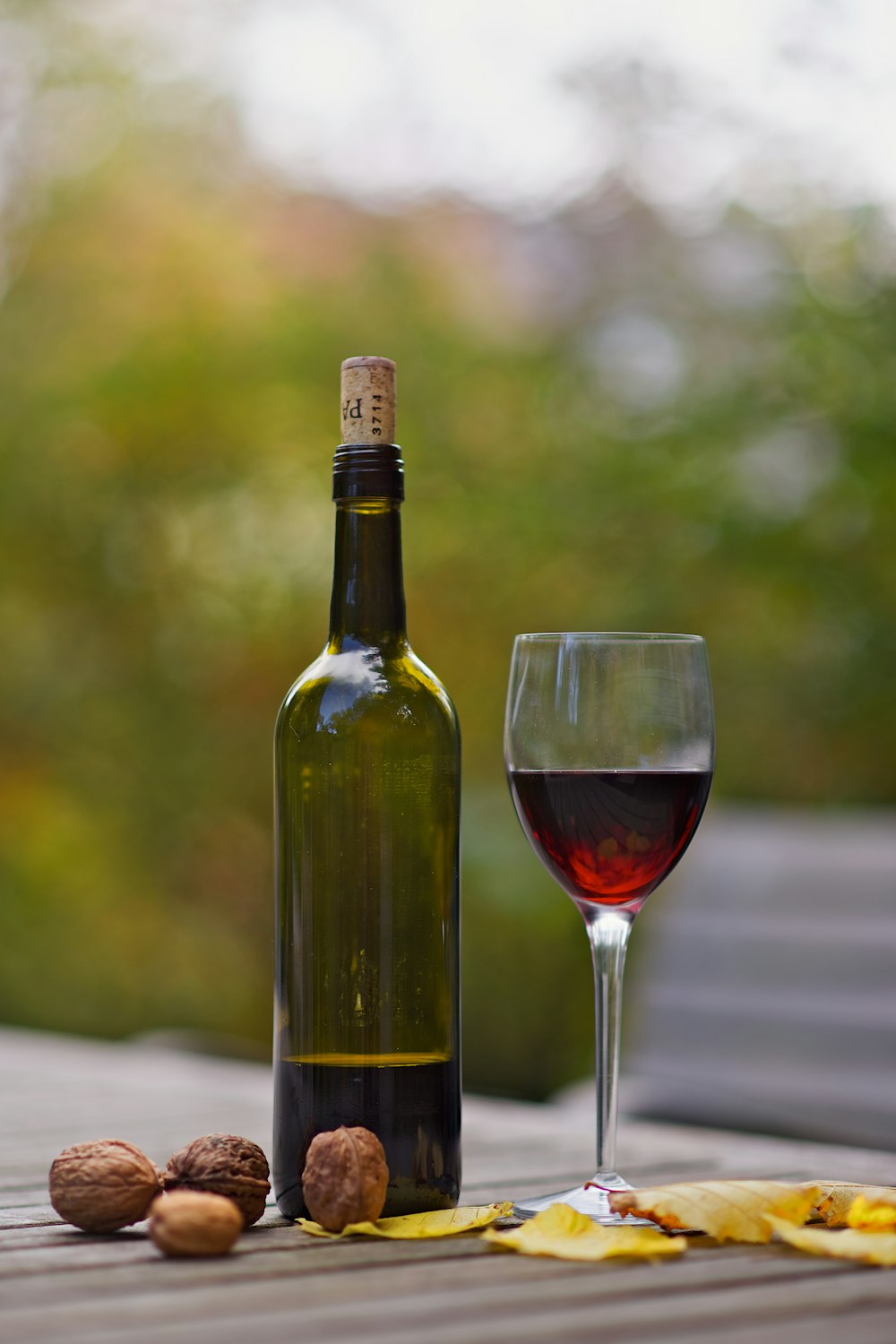 茶色の木の表面にワイングラスの横のワインボトル