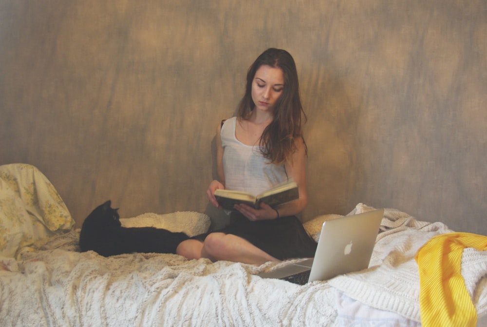 woman wearing white and black tank midi dress reading book on bed