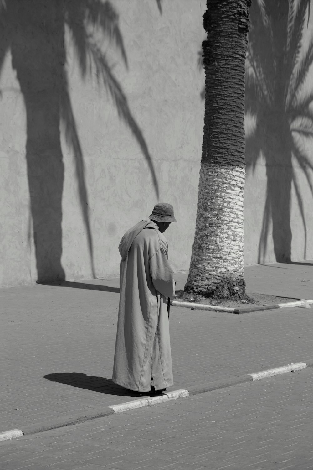 grayscale photography of man standing near tree