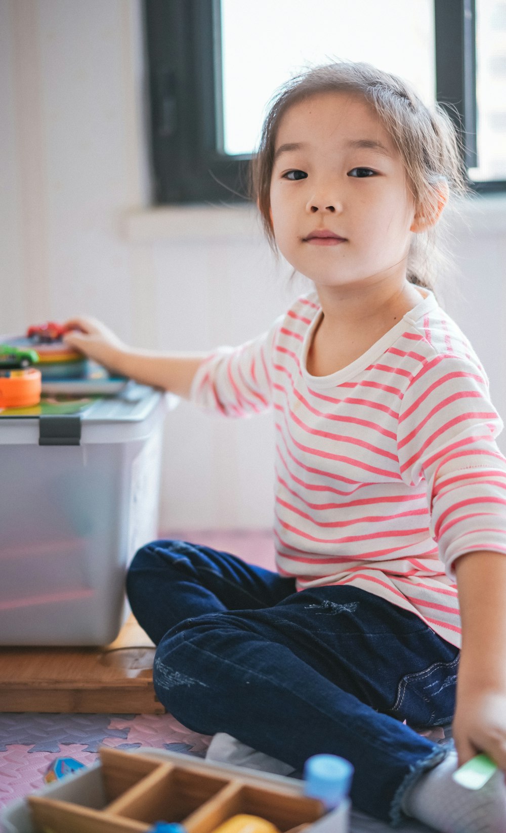 girl sitting on floor beside toys