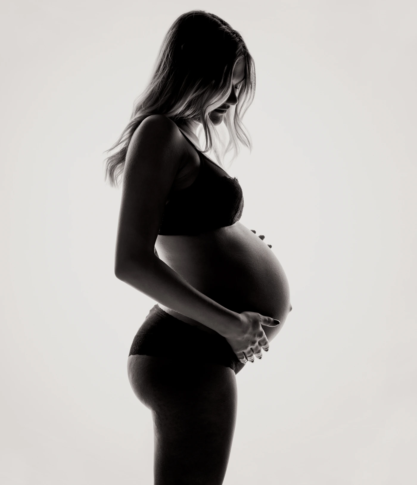 Expectant mother gently holding her pregnant belly in a calm studio setting