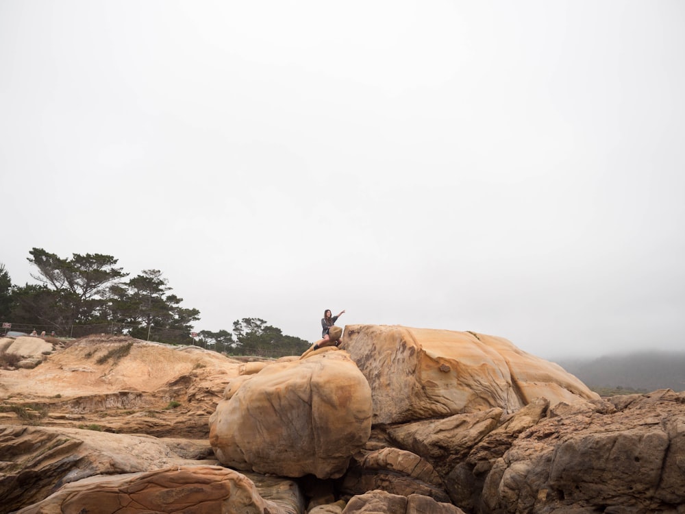 person sitting on brown rock