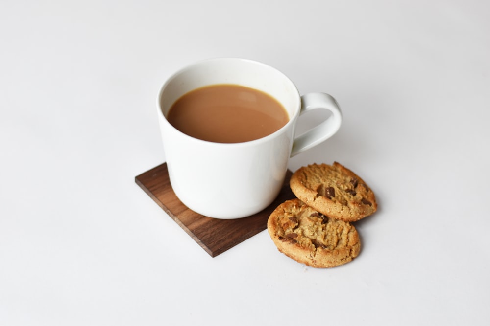 mug with coffee and two cookies on brown coaster