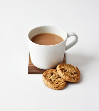 white ceramic coffee mug beside cookies