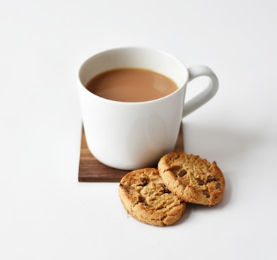 white ceramic coffee mug beside cookies