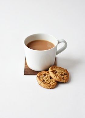 white ceramic coffee mug beside cookies