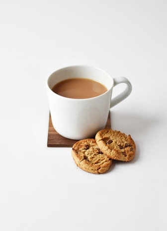 white ceramic coffee mug beside cookies