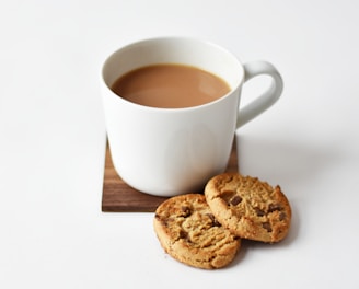 white ceramic coffee mug beside cookies