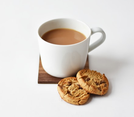 white ceramic coffee mug beside cookies