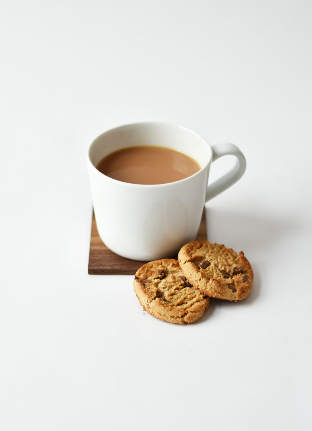 white ceramic coffee mug beside cookies