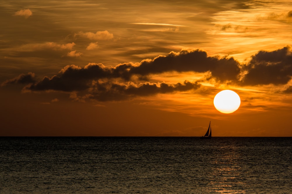 silhouette of sailboat on sea during golden hour