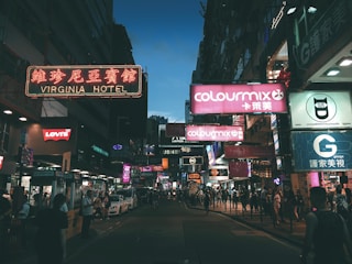 A glowing storefront sign illuminating a busy city street at dusk.